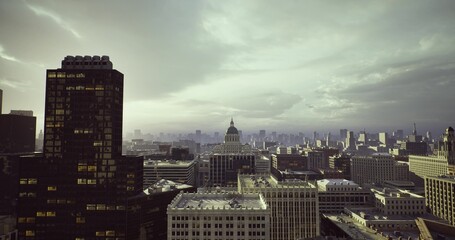 Fototapeta premium foggy city skyline with dome emerging through haze, muted morning light softens rooftops and streets, transit corridors and avenues visible beneath low clouds,