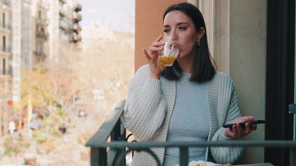 Fototapeta premium Woman On Balcony Drinking Orange Juice Outdoors
