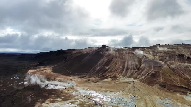 Aerial drone view of steaming fumaroles and sulfur vents in the Hverir geothermal area near Namafjall. White steam rises from mineral stained earth in an otherworldly volcanic environment