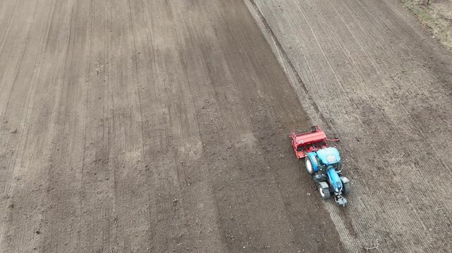 Aerial Drone View of Tractor Seeding Crops on Agricultural Field in Spring