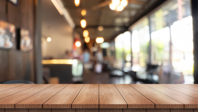Empty wooden table top with lights bokeh on blur restaurant background.