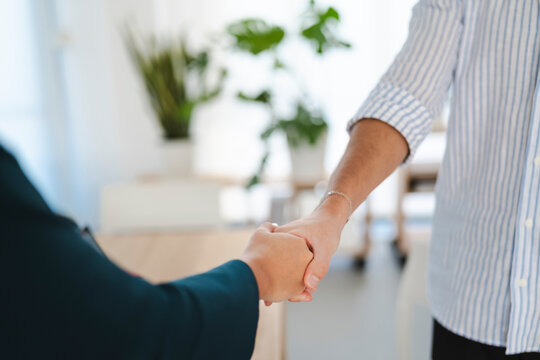 Two people shake hands in a modern office setting, symbolizing agreement and partnership.