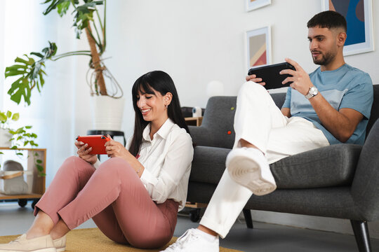 A young couple enjoys a moment of fun playing video games together in a bright, modern living room.