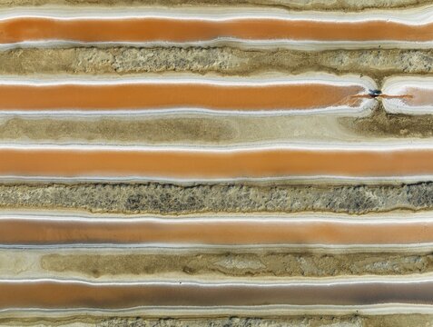 Saline ponds at the salt works near Chiclana de la Frontera. The orange-red colour depends on the level of salinity and is directly caused by the algae Dunaliella salina and brine shrimp. Aerial view. Drone shot. C&aacute;diz province, Andalusia, Spain