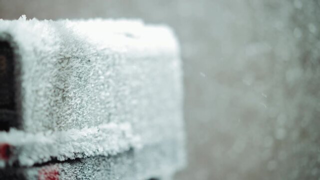 Frosted electrical box in nuclear winter closeup of frozen meter encrusted with hoarfrost, falling snow, icy texture, cold blue tones, abandoned industrial scene, eerie isolation and emergency signal
