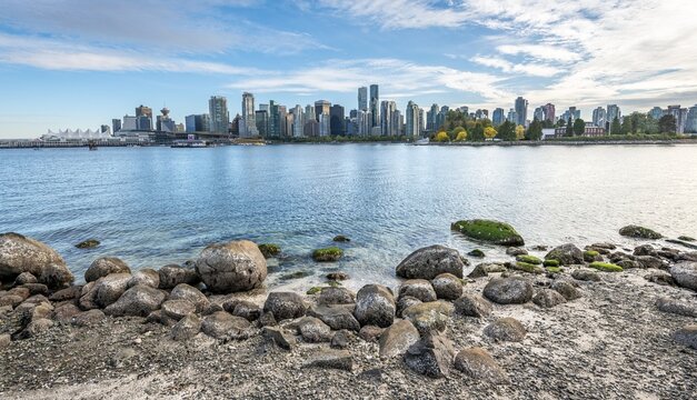 Stones on the coast, view across the sea from Hallelujah Point to skyline with skyscrapers, Stanley Park, Vancouver, British Columbia, Canada