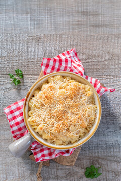 Warm baked macaroni and cheese served on a wooden table with checkered napkin