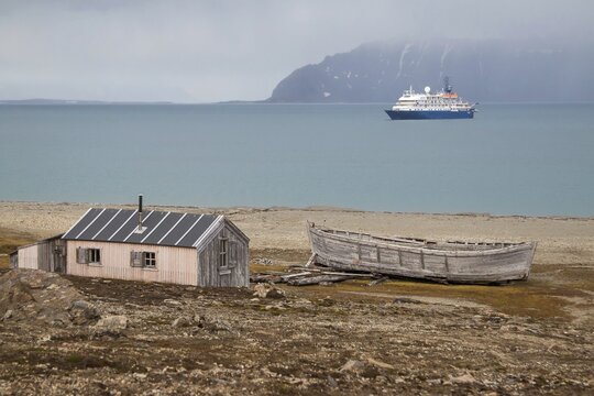 Former mining station Calypsobyen, wooden barrack with wooden boat, view of Bellsund, Spitsbergen Island, Norway
