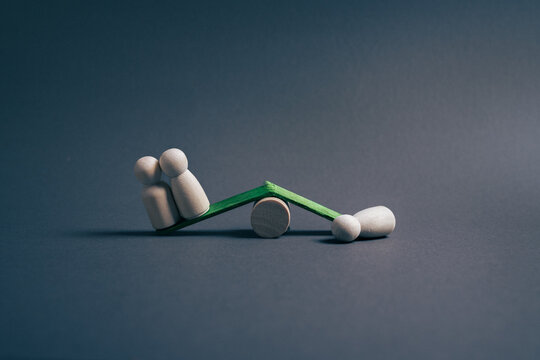 Imbalance of power concept with wooden figures on seesaw, unfair advantage and inequality