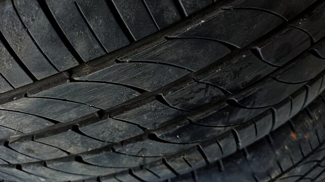 ​Close up of black rubber tire tread pattern. Detailed texture of a car or vehicle tire surface, suitable for automotive and transportation themes