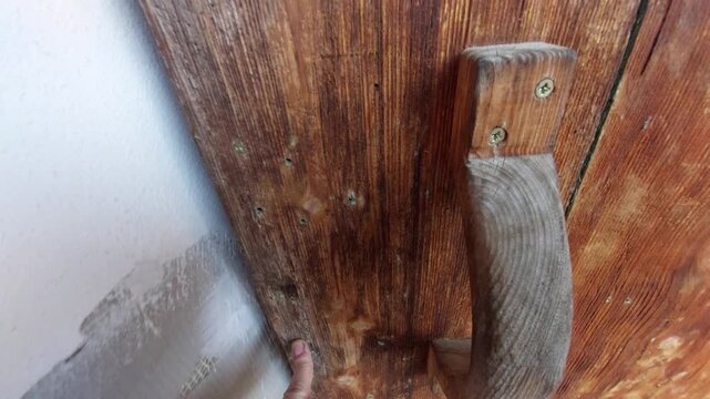 Detail of weathered wooden gate with rustic handle and visible wear