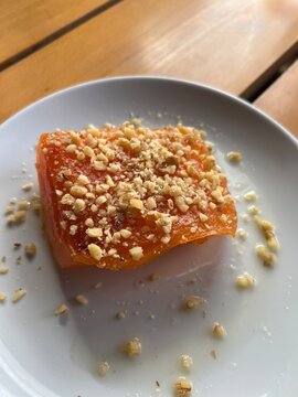 Traditional Turkish Quince dessert with crushed walnuts.

Description: A slice of slow-cooked, syrup-infused Turkish quince dessert (Ayva Tatlisi) served on a white plate and garnished with crunchy cr