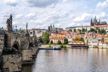 Fototapeta premium Panoramic view of Prague historic Mala Strana district, Prague Castle, the Vltava River and Charles Bridge in summer under a blue sky with white clouds, Prague, Czech Republic 