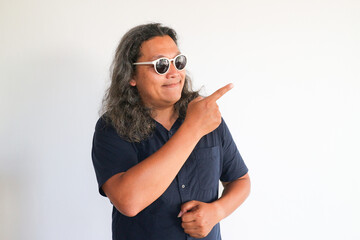 Fototapeta premium Asian man showing a direction with point finger on an siolated white wall
