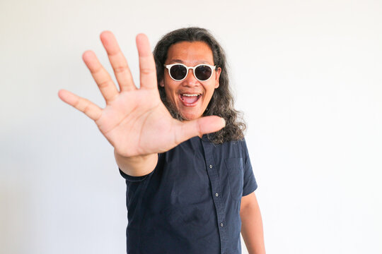 Asian man showing five fingers sign on a white wall isolated background