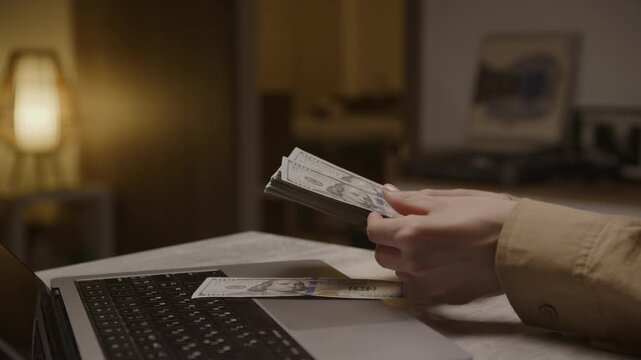 Counting cash beside laptop at home