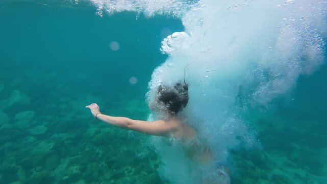 A young caucasian woman jumping from a boat into the clear turquoise waters of a tropical bay on Pr&iacute;ncipe Island, S&atilde;o Tom&eacute; and Pr&iacute;ncipe. 4k slow-motion video.