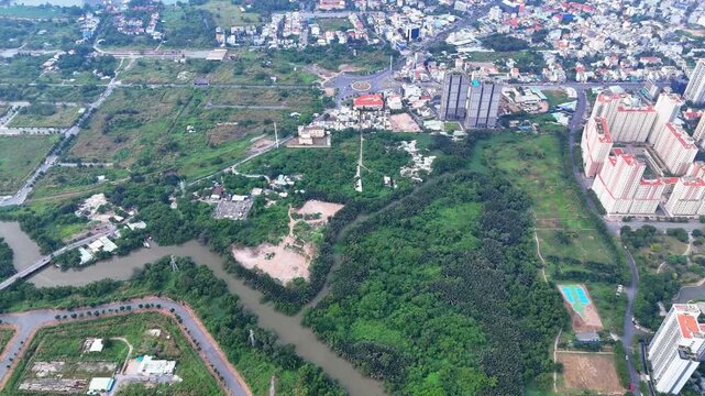 Aerial view shows winding river surrounded by lush greenery. Modern high-rise buildings rise near dense forested areas. Mixed-use zones blend urban development with natural landscapes