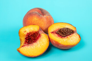 two peaches, one whole and one broken into 2 halves, one half whole and one half pitted, on a deep blue background