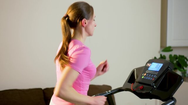 Female runner training on treadmill with digital control panel in home fitness space. Steady indoor cardio workout supporting endurance and everyday physical activity. Active lifestyle discipline and