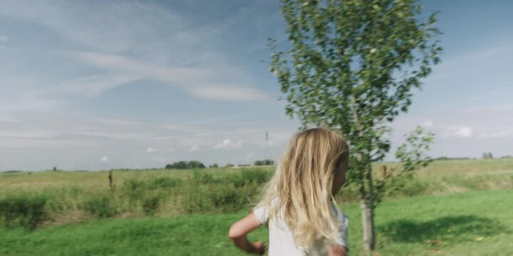 Boy running with a paper airplane in field on summer day