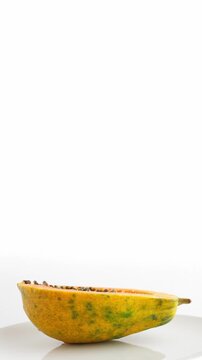 Ripe half cut papaya fruit. Rotate on white background. Vertical footage