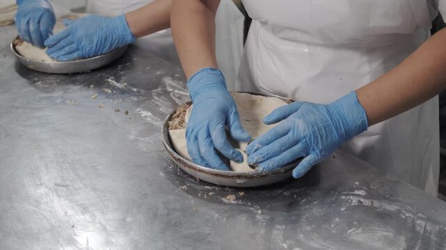 Close-up of professional baker's hands skillfully preparing a handmade pie in a commercial kitchen