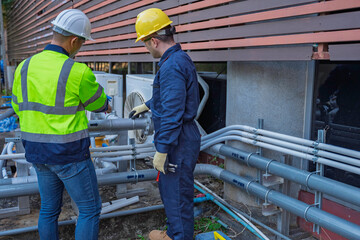 Two professional engineers inspecting industrial air conditioning system outside. Construction...