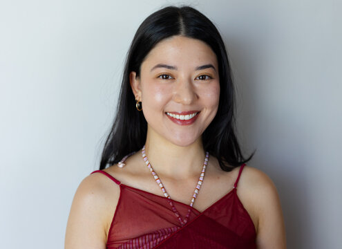 Vertical video: Smiling woman after cue, facing camera in studio, maroon top, necklace, gold hoops