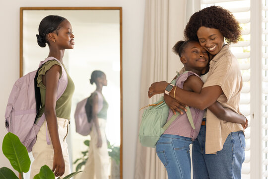 Vertical video: Hugging adult woman embracing child before school in entry in jeans with backpacks