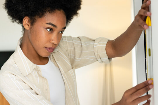 Woman placing spirit level on doorframe, activating animated overlay guiding DIY alignment