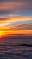 Fototapeta premium Vibrant sunset colors illuminate dense cloud layers seen from above high mountains