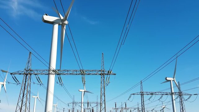 Wind Turbines and Power Lines Under a Clear Blue Sky, Generating Renewable Energy