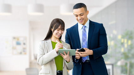 スマートフォンとタブレットを見ながら話すビジネスパーソン 男女のビジネスコミュニケーションイメージ, Business Colleagues Discussing While Looking at Smartphone and Tablet © Trickster*