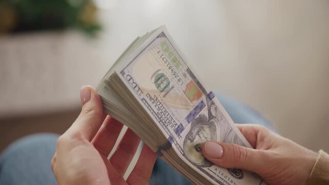 Hands holding thick stack of dollar bills