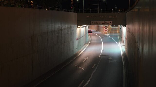 Cars driving through an illuminated underground tunnel at night