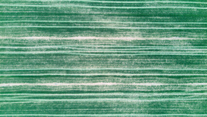 Drone view of cultivated farmland with horizontal green stripes formed by planted rows. Abstract agricultural field pattern suitable as natural background texture. © Ekaterina