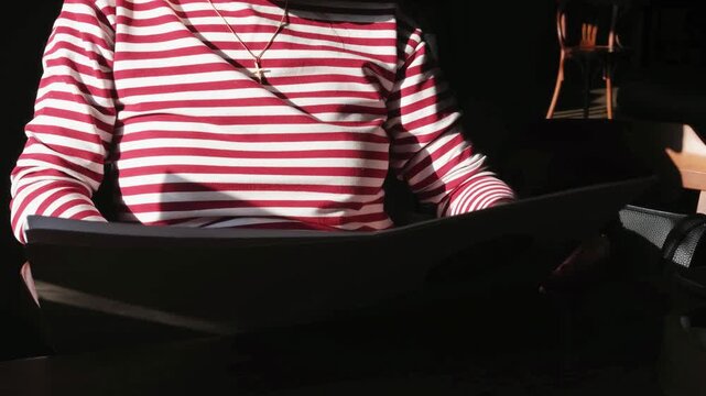 Woman sitting at cafe table reading and browsing menu before ordering food. Close view of customer choosing dishes and drinks in restaurant