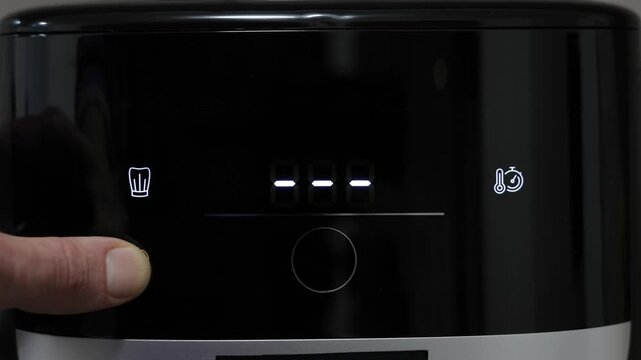 Human finger pressing start button on digital air fryer panel. Digital air fryer interface display. Menu and settings before start cooking.