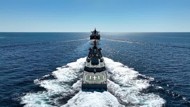 Naval destroyer escorts tanker across open ocean water on sunny day military escort duty patrol ship escort movement journey voyage ocean