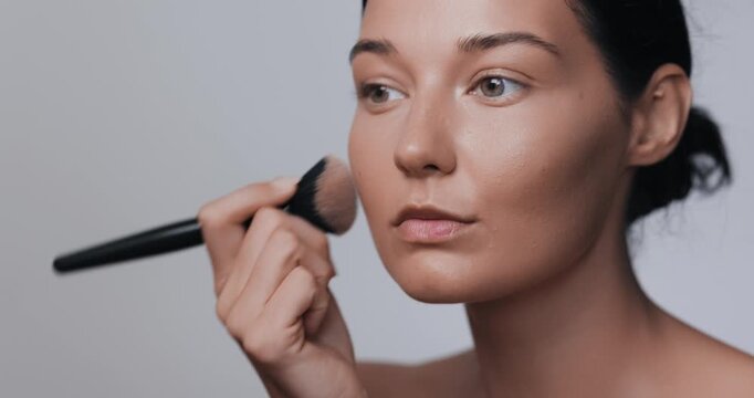 Close-Up Woman Applying Blush Makeup in Studio Beauty Routine