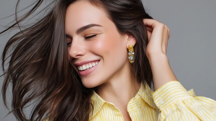 Fototapeta premium woman with brunette hair and golden earrings smiling on grey background