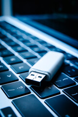 USB flash drive lying on a laptop keyboard as a concept of cyber security and digital data...