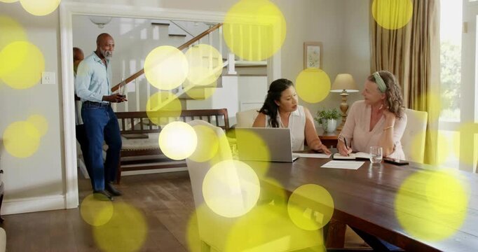 Women reading papers on table when man coming placing device starting tech demo with yellow bokeh