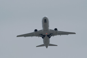White passenger plane flying in cloudy sky. White aircraft against cloudy background, aviation travel
