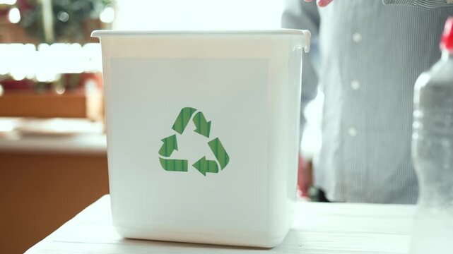 Man sorting plastic bottles and paper waste into recycling bins at home kitchen, 4K 10-bit.	
