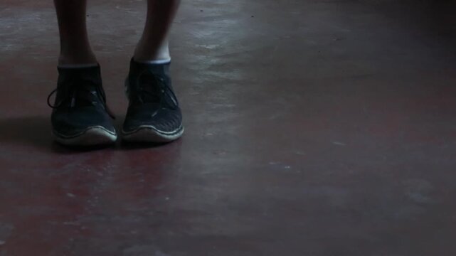 Close up of athlete feet jump roping in dark industrial gym during intense cardio workou