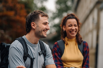 Obraz premium Two students laughing together outdoors while wearing backpacks