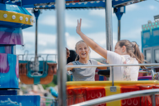Two girls waving from amusement park ride