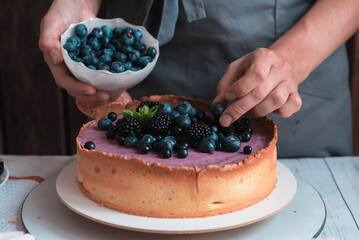 Baker decorating berry cheesecake with fresh blueberries